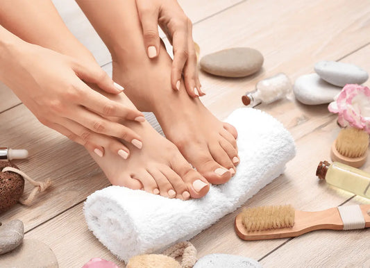 Woman Touching Feet on Towel by Home Foot Care Products.